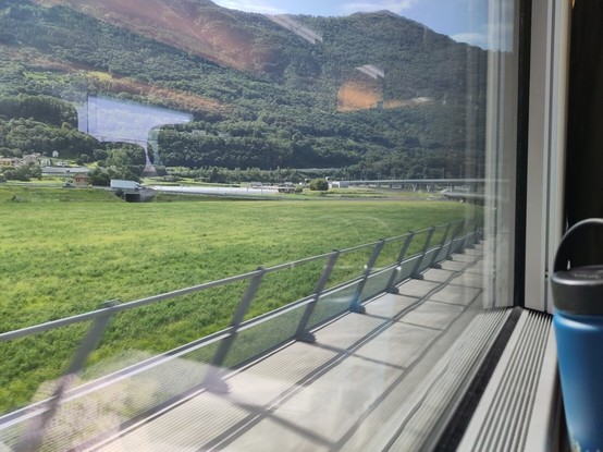 Foto. Blick aus einem Zug-Fenster, zwei Tunnelportale sind erkennbar.