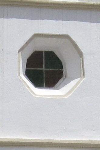 An octagon window in a deep recess in a white wall.