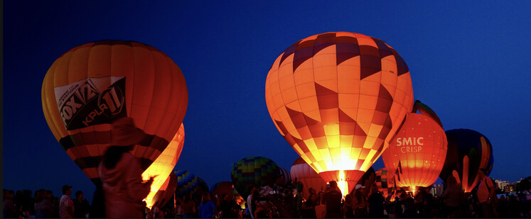Rich blue skies serve as the backdrop for the colorful balloon glowing from flames during the St Louis Forest Park Balloon Glow.