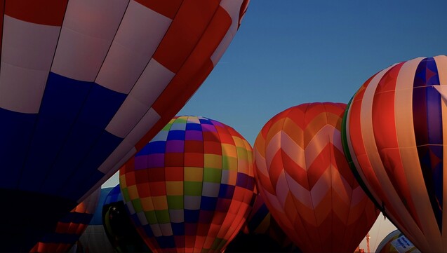 Twilight photo of the colorful hot air balloons clustered together during the St Louis Forest Park Balloon Glow