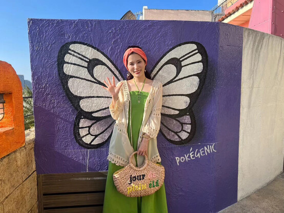 Chiemi posing behind a wall with Buterfree wings with text written: Pokegenic.
