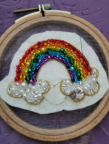picture of a rainbow made with beads on a wooden frame