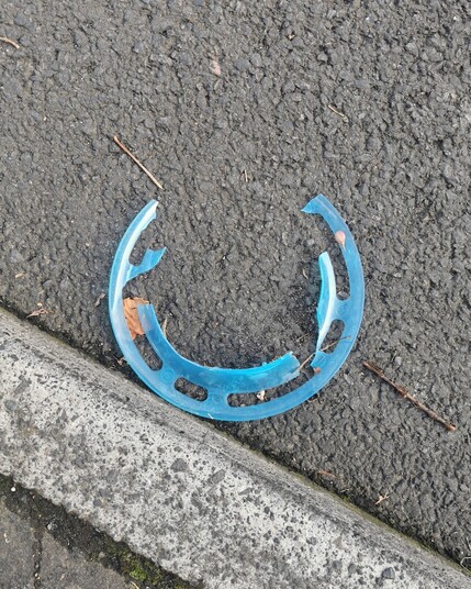 Litter. A blue plastic circular object. It has become broken and is now an incomplete circle.