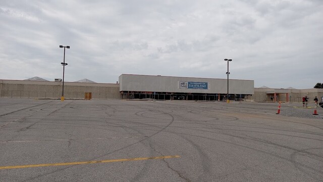 former site of a large Kmart store, fenced off and with windows and doors removed to prepare for tearing down