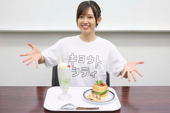 Rie shows off a meal that contains a melon shake and a burger that looks like a pizza too while smiling.
