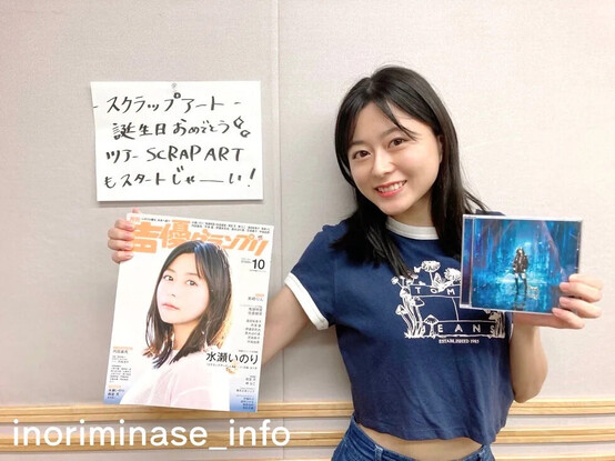 Inori smiling as she shows a magizine featuring herself and holding her next single.

Text written on paper:
スクラップアート
誕生日おめでとう
ツアーSCRAP ART
もスタトジャーい
