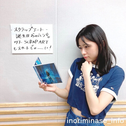 Inori looking at the single thinking.

Text written on paper:
スクラップアート
誕生日おめでとう
ツアーSCRAP ART
もスタトジャーい