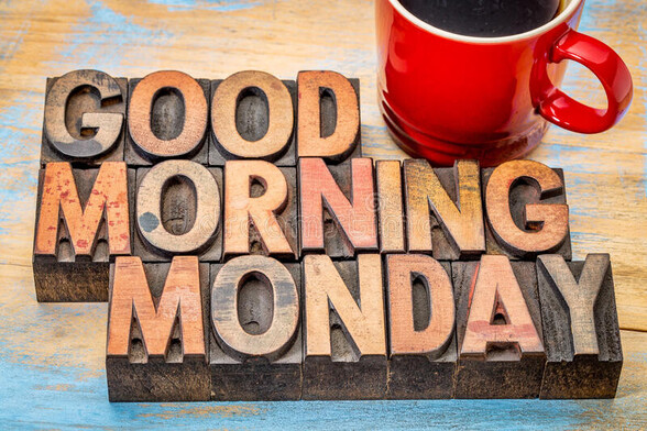 An image that says good morning Monday. The words appear to be wood blocks of some sort. There is also a red coffee cup in the top right corner that's filled with coffee.