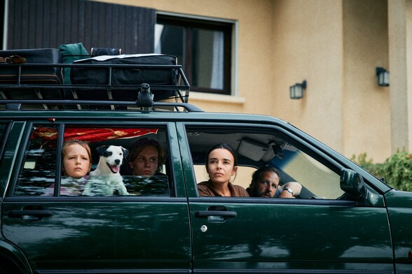 A mum a dad and two kids with a dog are in a car looking out of the windows in this still from For Night Will Come