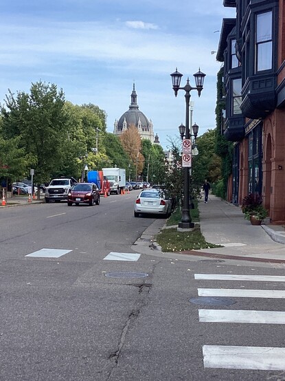 A street view of the dome of the Cathedral in St Paul, MN, USA behind trees and parked cars.