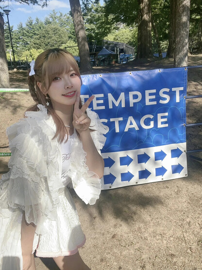 Liyuu talking a picture with a v sign at the tempest stage event sign.