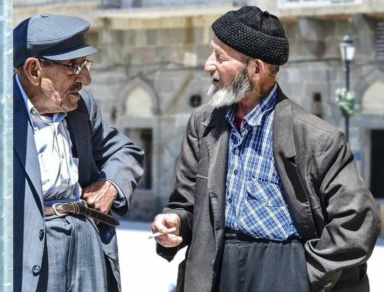 How old are you? Photograph of two old men standing and talking.