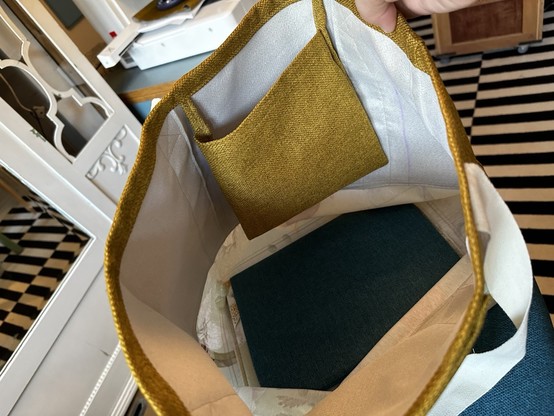 An inside look of the tote bag. It has a removable bottom (in thick cardboard, protected by a sleeve), and an inner pocket.