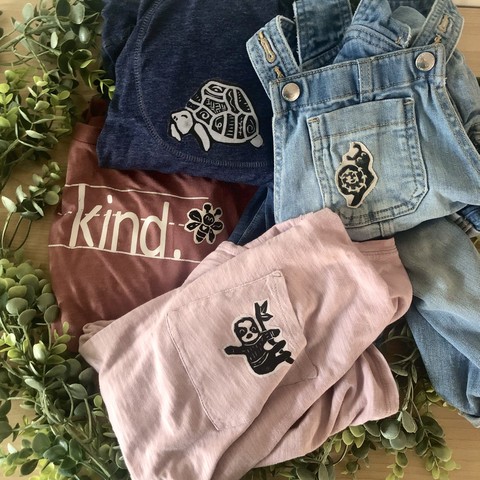 A photo of various pieces of clothing with stamped patches (a sloth, a turtle, a bee, and a snail)