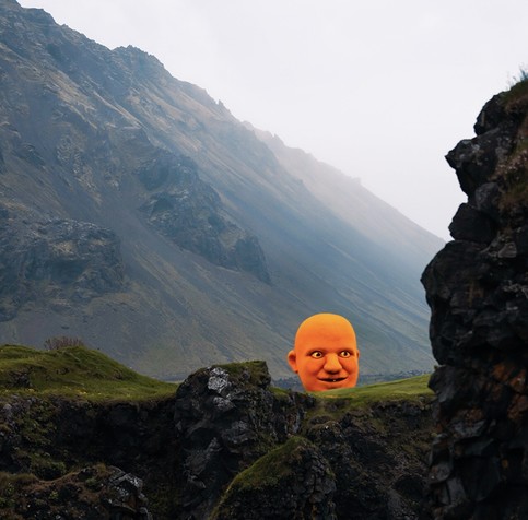 Photo of a rocky coastline where I’ve used generative AI tools to insert an orange monster at the top of a grassy cliff. 

This monster is kind of like a Daruma— it’s just a giant orange head on the cliff, looking off to the right, with a somewhat mischievous grin. It bears a startling resemblance to me, actually.