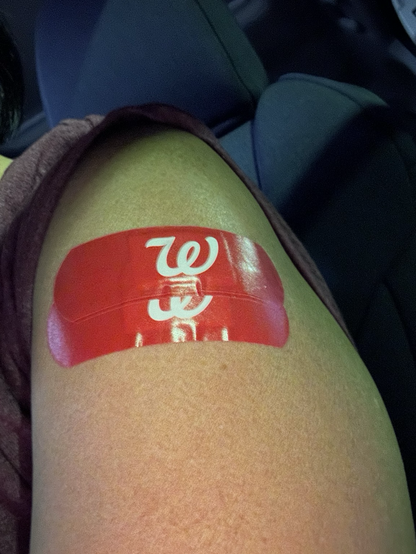 Two red Walgreens bandages on my arm after getting my flu and updated COVID shots.