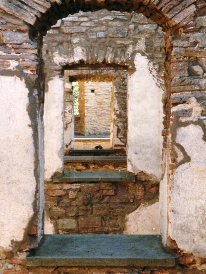 Blick durch vier hintereinanderliegende Fensteröffnungen in alten Schlossmauern.
Ein fünftes Fenster ist stark versetzt, so dass es nur einen schmalen Streifen zum Durchblick ins Grüne freigibt.