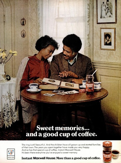 An aged couple looks through a photo album and enjoys some coffee