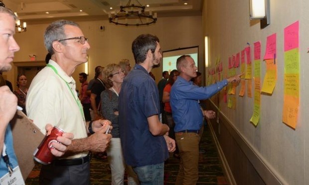 Sometimes, the right choice for events is analog tools, as shown in this photograph of conference attendees posting and reviewing topics for sessions written on sticky notes.