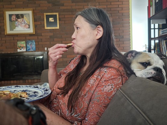 My wife eating on the couch, with our bulldog wedged into the cushions behind her.