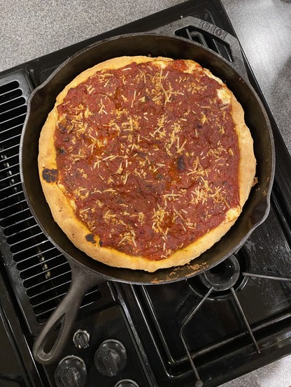 An overview photo of a deep dish pizza, cooling on the stove top