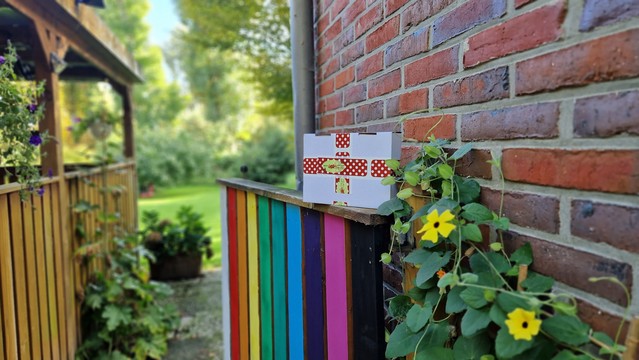 Paket auf der Brüstung des bunt gestrichenen Gartentors im Hintergrund sonniger Garten