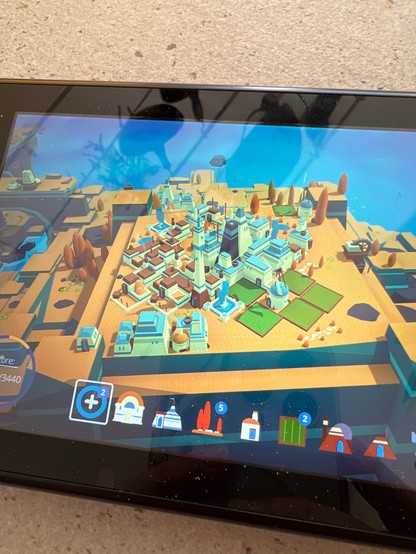 The screen of a Nintendo switch shows a game, with low poly graphics and a town being built upon an island.