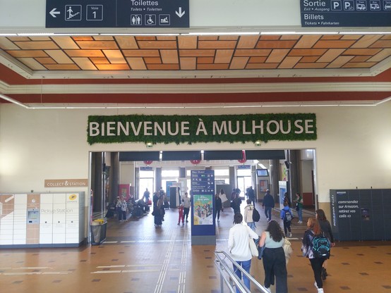 Station Mulhouse-Ville with a huge "Bienvenue à Mulhouse" banner.