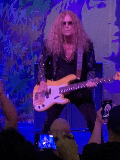 Bass player and singer Glenn Hughes playing the bass on stage.