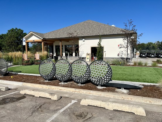 One of three “Ace!” sculptures, installed. Each sculpture consists of four stop-motion views of a golf ball rolling into the cup. The dimples of the ball’s surface are represented by rounded hexagonal cuts, with a crescent of dark metal for the shadow.