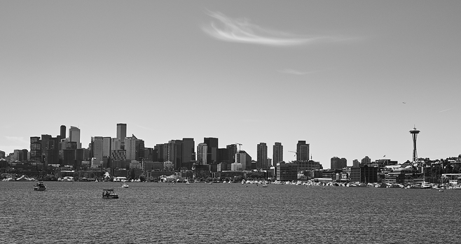 View across Lake Union in Seattle to the central part of the city on a beautiful day in May. The famous Space Needle is on the right, there are some boats on the lake, and a whispy cirrus cloud above. One can even see a jet above the Space Needle heading toward Sea-Tac to land.
