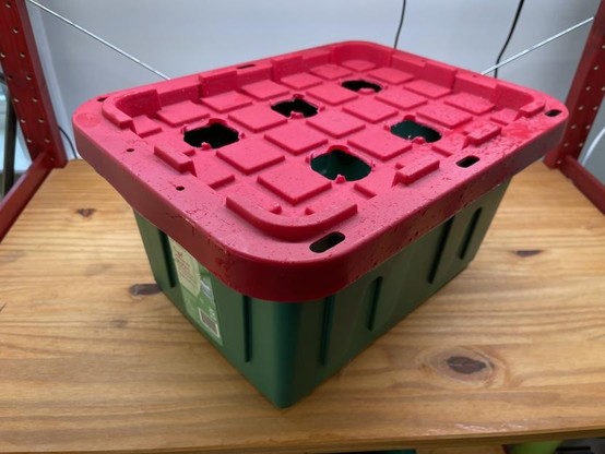 Bin with lid with holes in it put together and placed under grow lights. The lid is red and the bin is green. They're the Christmas bins. But the color goes well with the hydroponic shelf. Aesthetics are important!