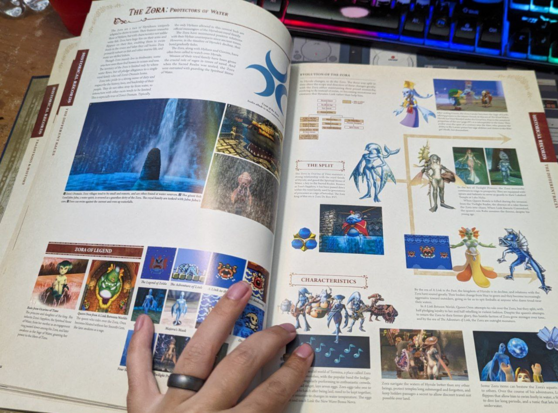 The Zelda encyclopedia is open. The pages show a history of the Zora aquatic fish people.