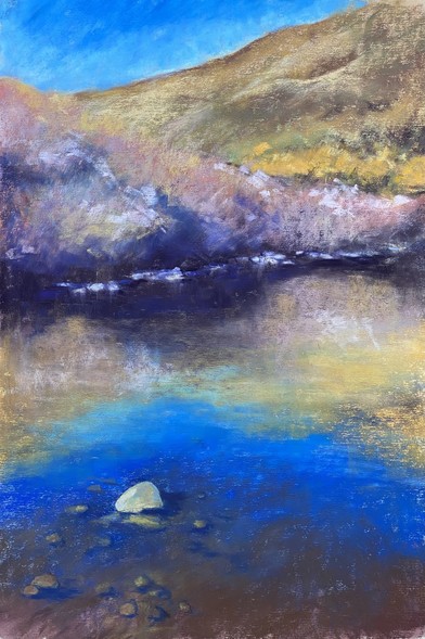 Vertically long pastel painting, work in progress. Blue sky reflected on the water, a lone rock in the river. Hills and mauve colored brushes in the background.