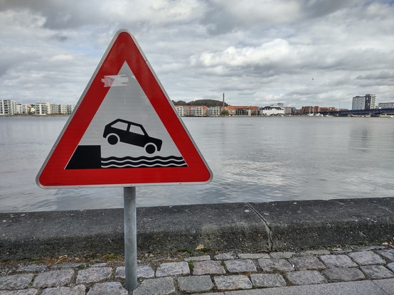 street sign warning drivers not to drive off the quay and into a river