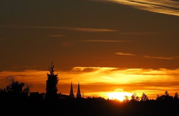 Foto kurz vor Sonnenuntergang aus meinem Zimmerfenster in Richtung KÃ¶ln-City. Die Sonne geht noch rechts von den DomtÃ¼rmen unter. 
Der Himmel im unteren Bilddrittel ist hellgelb bis orange. in der oberen BildhÃ¤lfte blaugrau.
Links unten im Vordergrund eine Tannenspitze