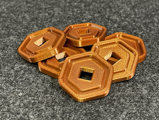 3d printed Robux coins from the Roblox video games, in metallic copper color filament