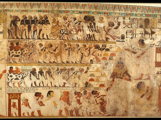 Image title: "Nubian Tribute Presented to the King, Tomb of Huy, detail, center section, by Charles K. Wilkinson (MET, 30.4.21)", 1353â€“1327 BCE

Caption: The Nubians were depicted as black, while the ancient Egyptians depicted themselves as a brownish-red color."