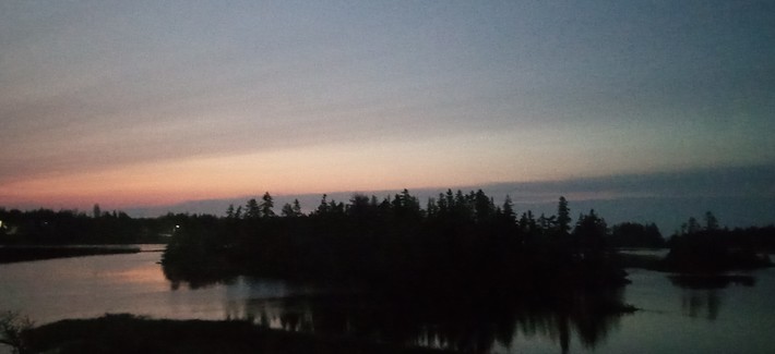 A stream of first light over the harbour, pinkish on the left, bluish on the right. An island rests close to the shore below. ( island was tired lol)