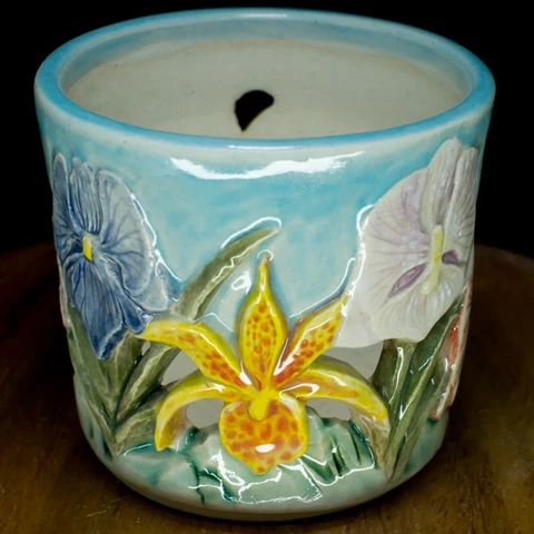 another view of the same pot, featuring a thin petalled orchid, which features yellow petals spotted with bright red.