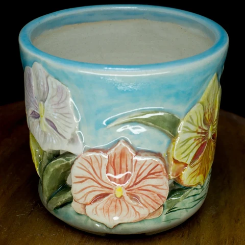 another view of the same pot, featuring a pale orange flower veined with red, along with a lavender one.