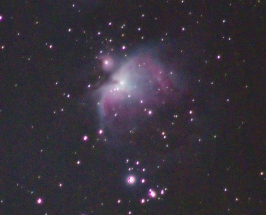 Purplish clouds of the Great Orion Nebula. Colourful star dots around it.