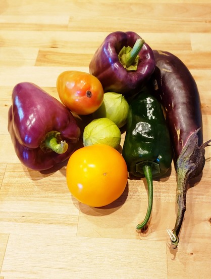 Two purple bellpeppers, a couple of tomatillos, a roma tomato, a small orange Djena Lees tomato, a big poblano, and a Japanese eggplant.