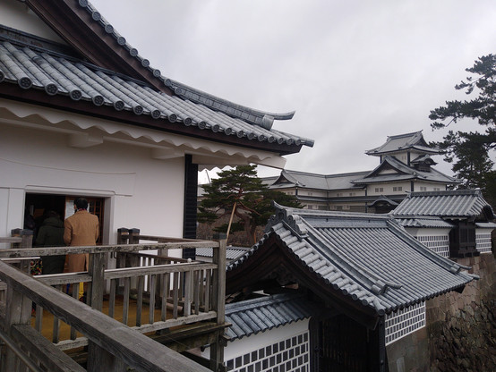 View of the rooftops of certain parts of the Kanazawa Castle area and associated buildings. Sloped roofs, most designed with a tubular design for supports with wavy pressed shapes; a slightly off blue or grey colour to them