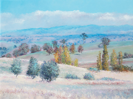 A peaceful autumn landscape in New South Wales, Australia, near Wee Jasper, with soft blue hills in the distance. There is a row of poplar trees amongst the gently rolling hills.