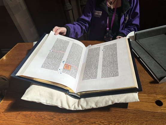A museum worker holds open a Gutenberg Bible.