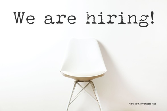 Schriftzug "We are hiring!" über einem leeren Stuhl.
