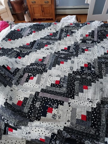 a quilt made of small white and black pieces with scattered red pieces as well