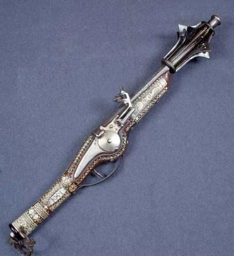 Pistola de chispa con una maza en el cañón formada por seis hojas metálicas puntiagudas y concéntricas.