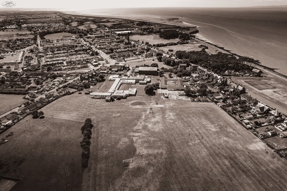 Aerial shot over Cumbrian town with coast in background. Sepia toned